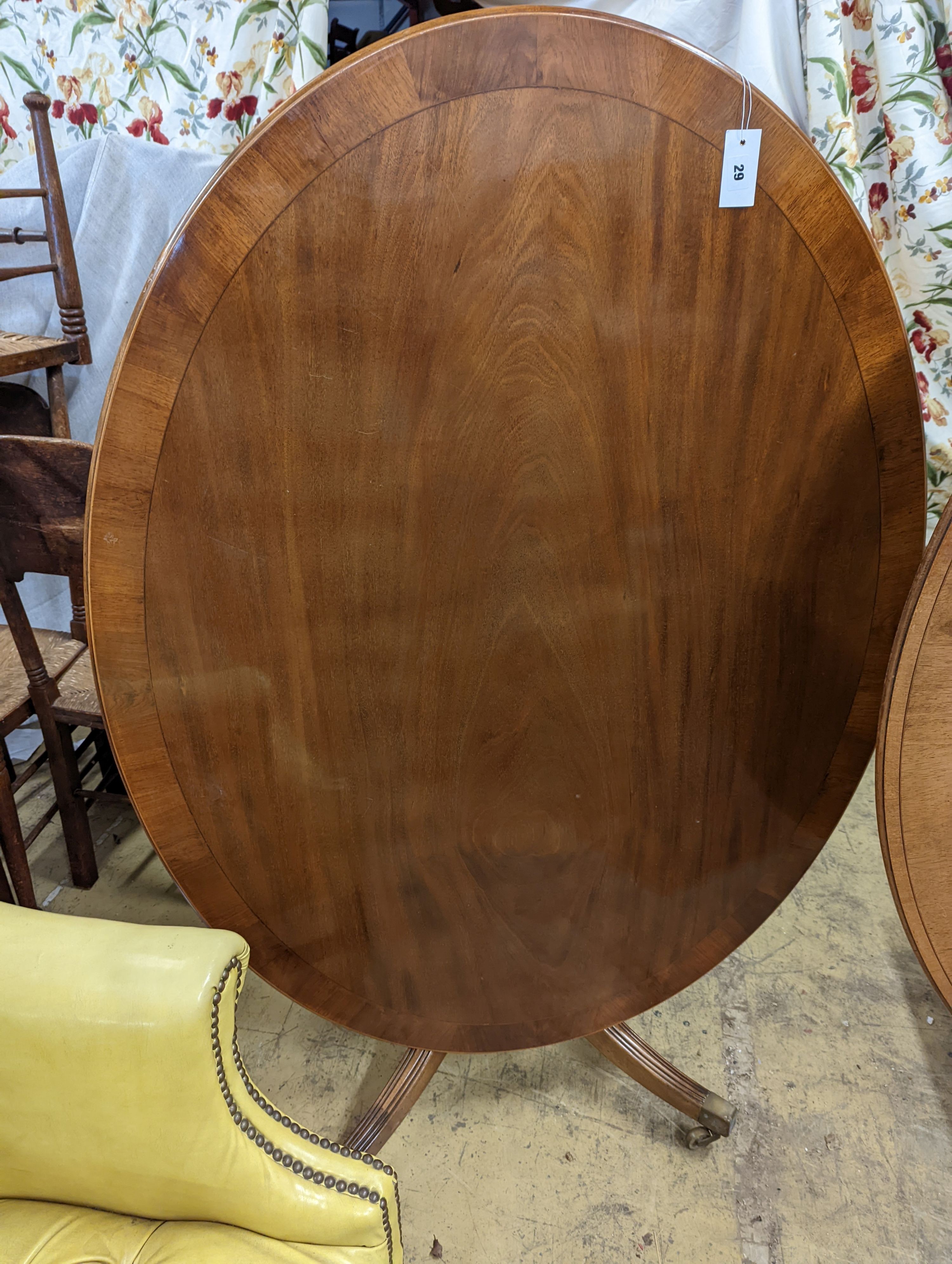 Attributed to William Tillman. A reproduction George III style oval mahogany pedestal tilt top dining table, width 105cm, length 135cm, height 72cm